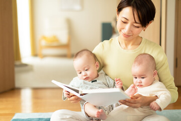 Obraz na płótnie Canvas 絵本を読む母親と双子の赤ちゃん