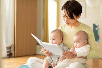 絵本を読む母親と双子の赤ちゃん