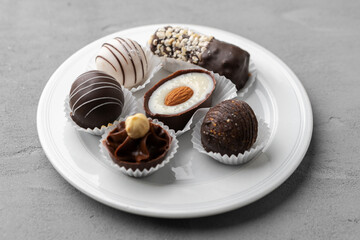 Chocolate candies in a white plate on gray background