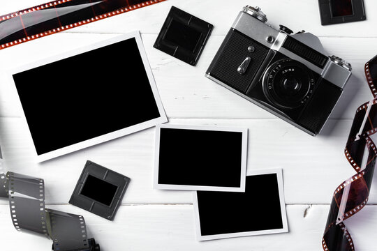 Old retro camera and photos on white wooden background