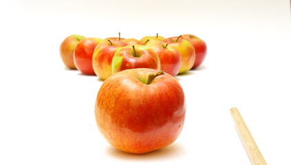 Apples in a triangle, one apple separately and a cue on a white background. Emulation of billiards. Selective focus.