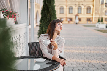 Obraz premium Young beautiful woman with smartphone sitting in the street cafe with coffee. Concept meeting, working, freelance