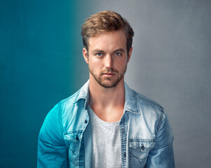 Obraz premium Live your life in full color. Portrait of a handsome young man with a blue overlay posing against a gray background in the studio.