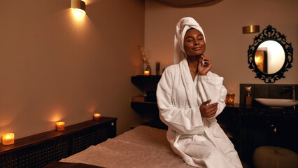 Pleased african girl touching herself in spa salon