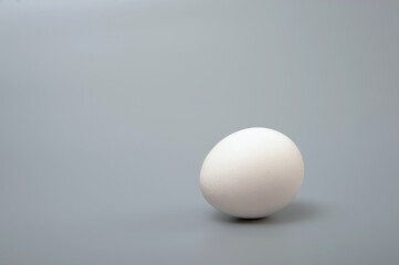 White egg on a gray background. Minimalism. Healthy food concept. 
