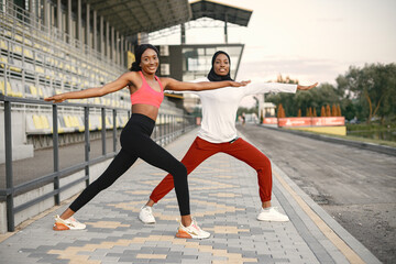 Two black women doing stretching on a stadium
