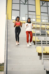 Two black women running down a stairs on a stadium