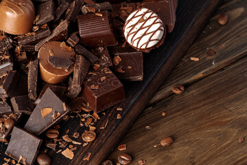 Chocolate pieces and candy on dark wooden table.