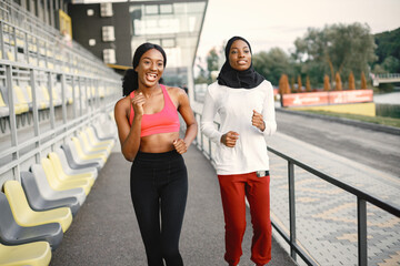 Two black women running on a stadium