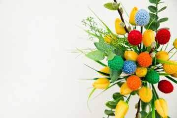 Fototapeta premium The breeze of spring. Easter composition with tulips and crocheted eggs. Featuring bouquets with handmade accents.