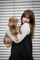 Girl petting small Dachshund dog in the street