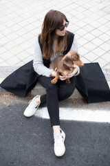 Girl petting small Dachshund dog in the street