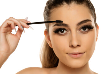 Fototapeta premium Young woman correcting eyebrow shape with brush,
