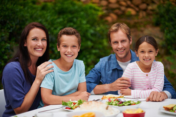 We always have dinner as a family. Portrait of a smiling family enjoying a meal on their patio.