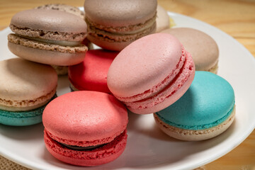 Close up macaron dessert pastel tones on white plate , Sweet and colorful french macaroons  on wooden background, Dessert.