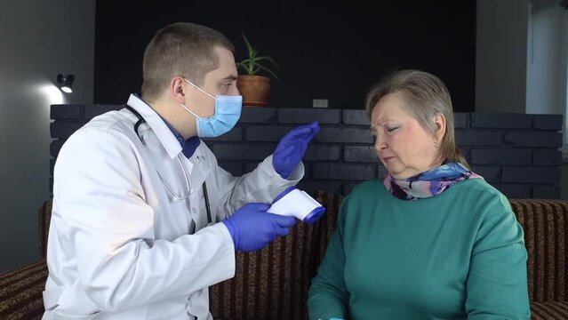 Non-contact thermometer. Doctor measures the body temperature of a senior woman. Therapist examines a woman who complains of fever and sore throat. Symptoms of covid 19, sore throat, flu and SARS.
