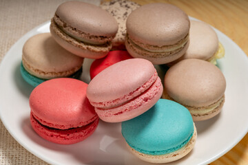 Close up macaron dessert pastel tones on white plate , Sweet and colorful french macaroons  on wooden background, Dessert.