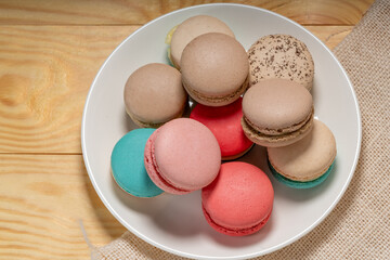 Fototapeta na wymiar Close up macaron dessert pastel tones on white plate , Sweet and colorful french macaroons on wooden background, Dessert.