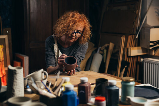 woman carving clay pot in her workshop