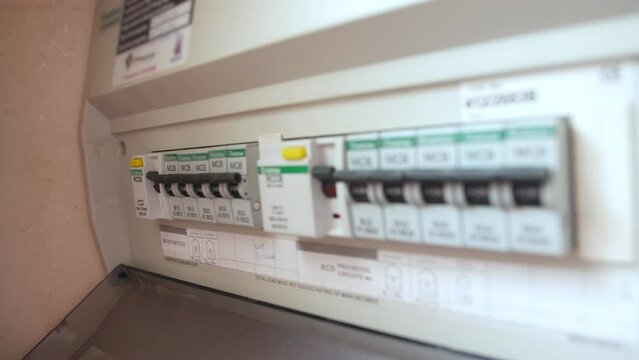 A man resets a tripped fuse in a power circuit breaker electricity fuses box