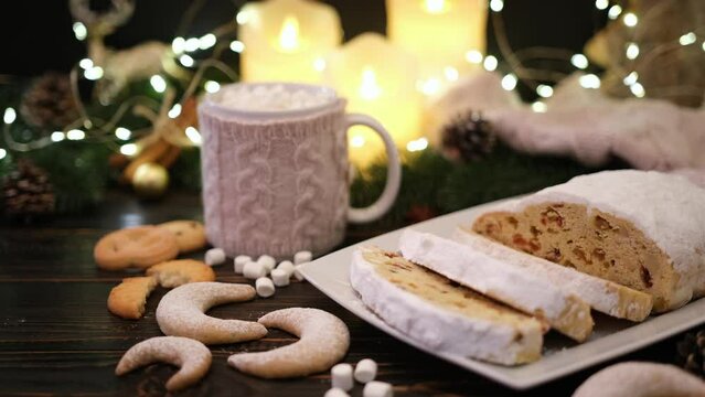 Sliced Traditional Christmas stollen cake with marzipan and New Year decorations on wooden background