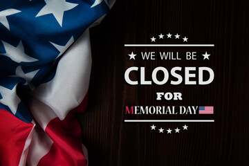 Obraz na płótnie Canvas Memorial Day Background Design. American flag on a background of wooden teable with a message. We will be Closed for Memorial Day.