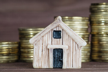 Toy house model against coins stacks background