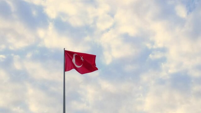 Turkish flag waving in blue sky with clouds , Republic Square in Antalya. A lively town square with equestrian statue of former President Ataturk surrounded by numerous cafes.