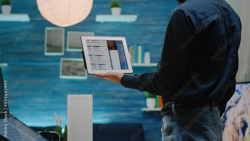 Poster Close up of architect using tablet with touch screen to analyze building model for architectural development. Man engineer working with device for construction layout and design.