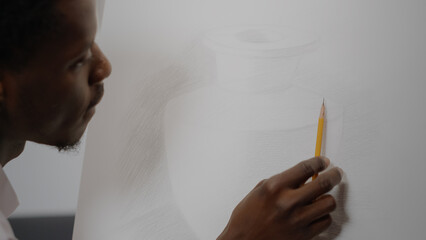 Close up of drawing of vase with black hand holding pencil on white fine art canvas in artwork...
