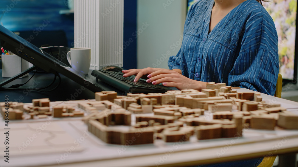 Poster close up of architectural desk with building model and touch screen monitor. woman architect analyzi