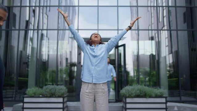 Winning business lady screaming raising hands up in crowded office city center.