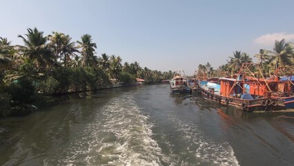 Fishing boats moored on banks of navigable canal at Alappuzha or Alleppey, India. Backward shot