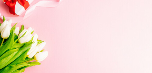 Mothers day gift. Spring white tulip flower, gift with red ribbon on flat lay pink background. Valentines, birthday, women or wedding day concept.