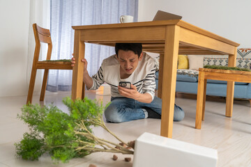 地震・災害で机に隠れる男性