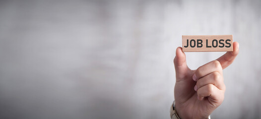 Hand showing Job Loss text on wooden block.