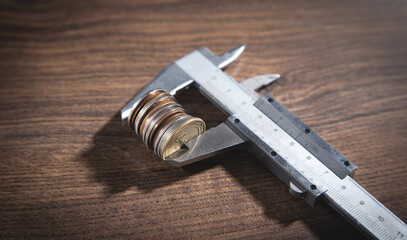 Vernier caliper and coins on the wooden table.
