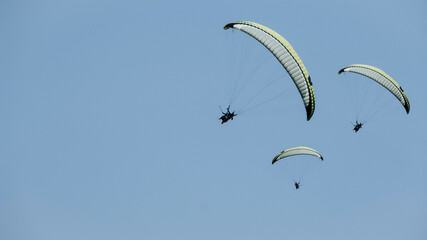 A paragliders on the sky background.