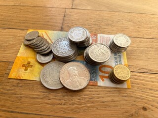 Stacks of Swiss francs and centimes on a Swiss banknote. Piles of Swiss coins laying on a banknote of Swiss franc. 10 francs CHF