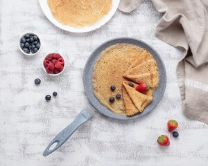 Pancakes with berries on the baking pan