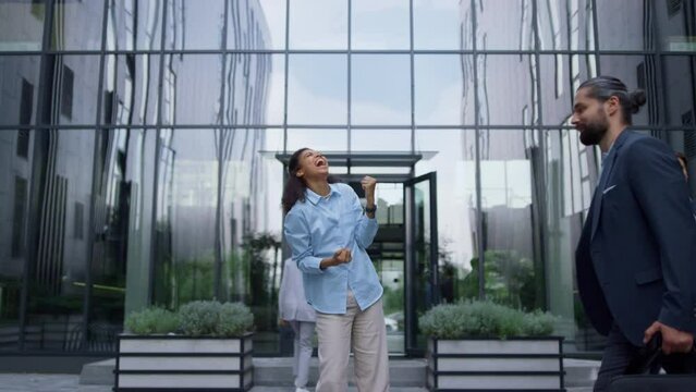 Excited business woman celebrating promotion in contemporary glass office facade