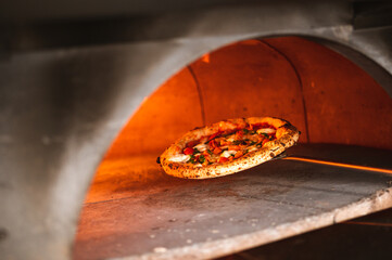 Wood fired artisanal pizza cooked in wood oven on rustic vintage chopping board served with fresh...