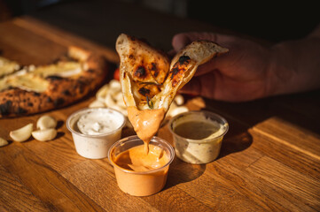 Wood fired artisanal pizza cooked in wood oven on rustic vintage chopping board served with fresh veg in summer sunshine with home made sauces and tasty ingredients vegetarian vegan pepperoni cheese