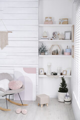Stylish room interior with rocking chair, wall shelves and beautiful Christmas decor