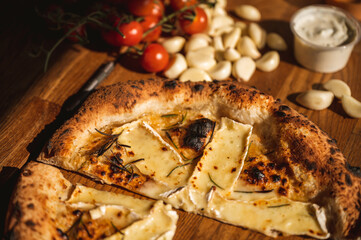 Wood fired artisanal pizza cooked in wood oven on rustic vintage chopping board served with fresh veg in summer sunshine with home made sauces and tasty ingredients vegetarian vegan pepperoni cheese