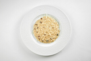 Risotto with mushrooms in a white plate on a white tablecloth