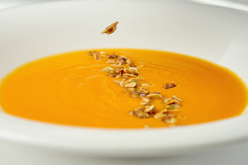 Chef decorates pumpkin cream soup in a white plate