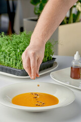 Chef decorates pumpkin cream soup in a white plate