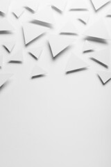 White paper triangles as abstract pattern in bright light with soft light shadows, border, copy space, top view. Airy tender softness modern background in future minimalistic style.