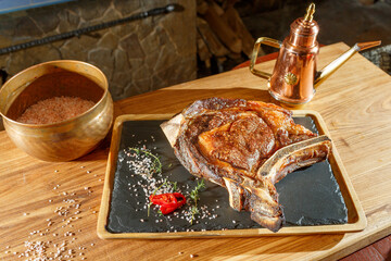 Wet-aged steak on a black plate with spices,rosemary  on a wooden table background 